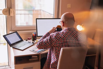 Bald man drinking coffee and working from home on his computer