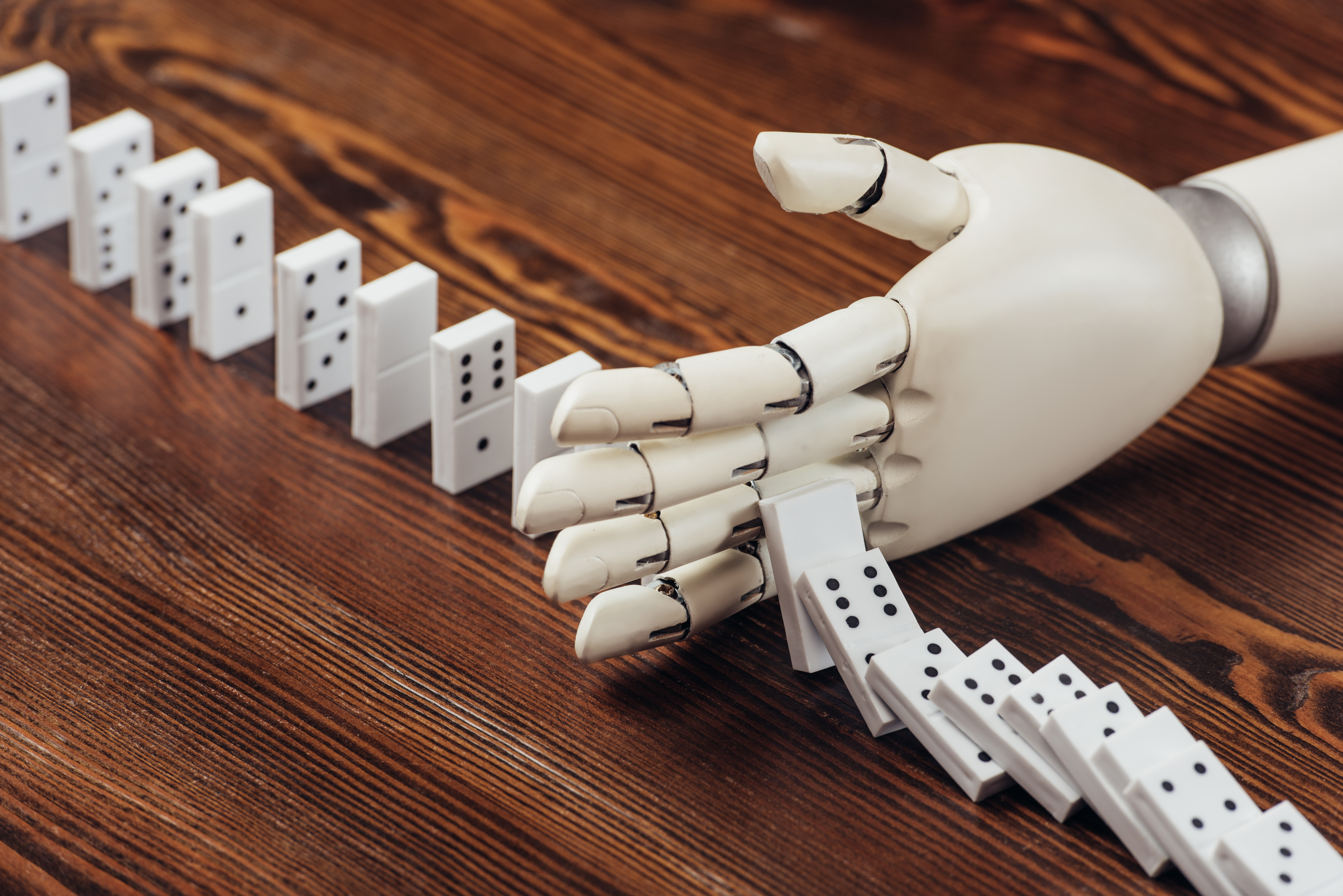 Robot hand stopping dominoes from falling over
