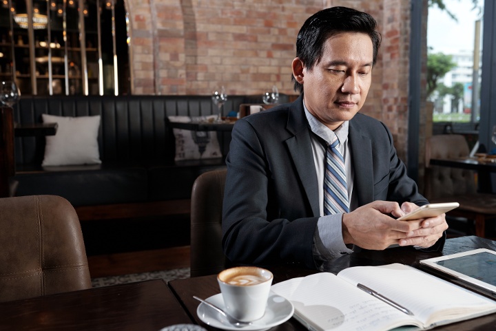 part-time business executive texting a client from inside a coffee shop